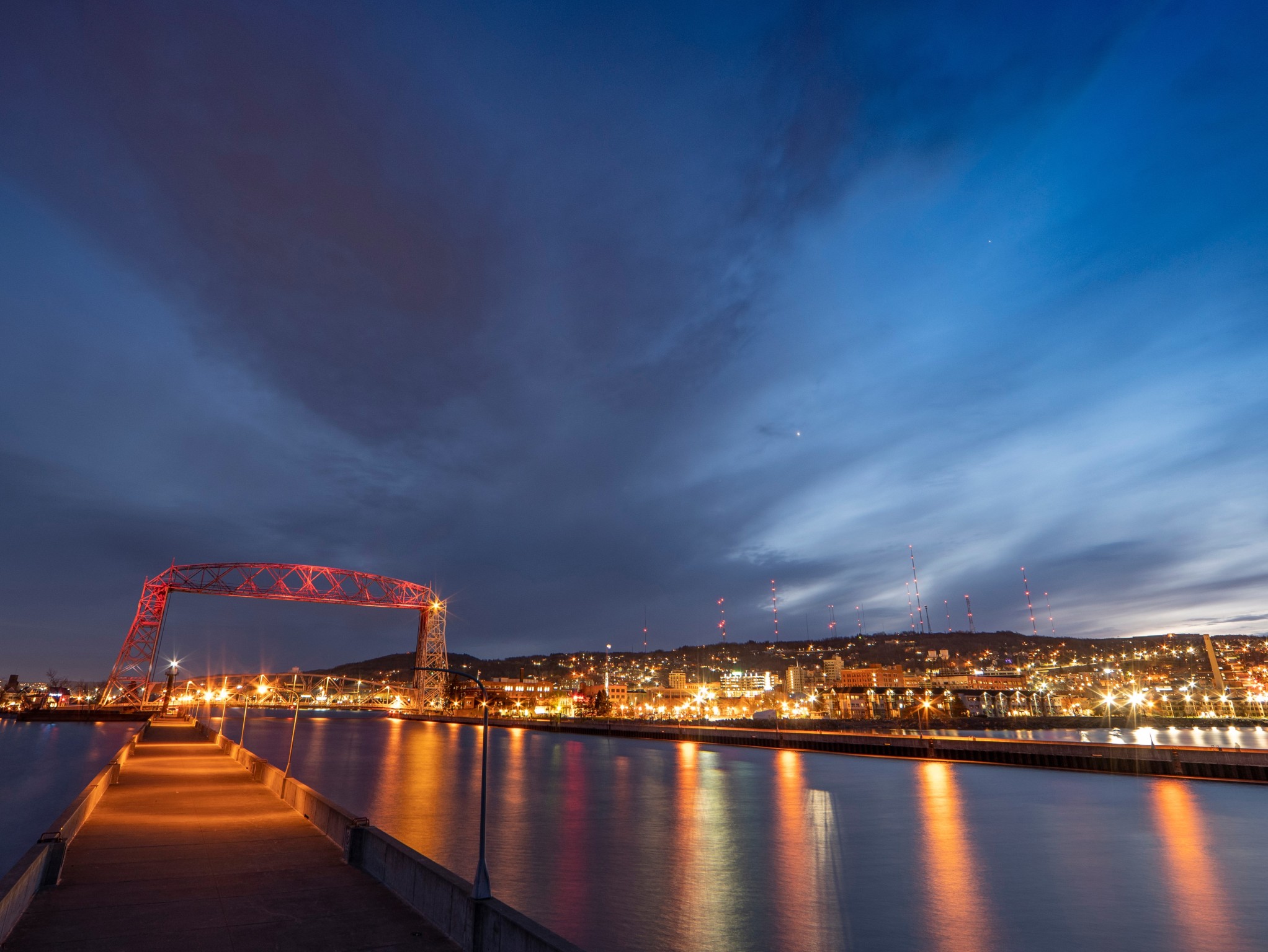 A night scene of the lift bridge lit up with maroon and gold lights.