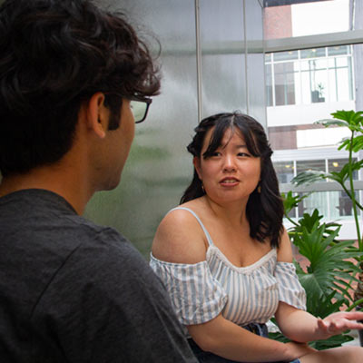 Male and female student talking near plan.