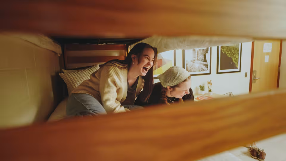 Two students smiling and laughing together in dorm room on campus