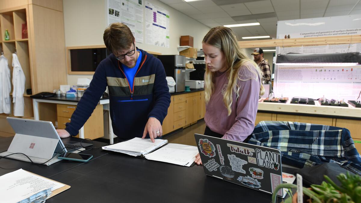 A professor and a student working at a chemistry lab bench with laptops